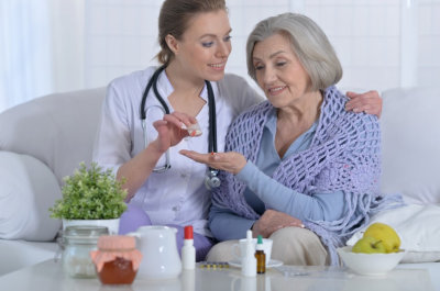 nurse giving medicine to senior woman